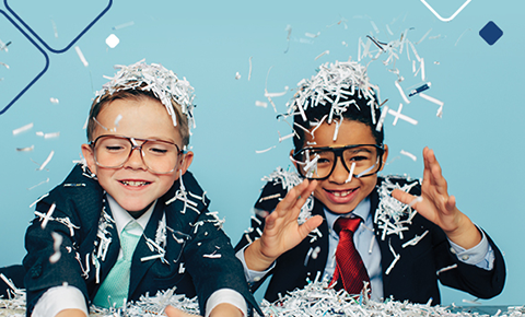 Two boys in suits tossing shredded paper