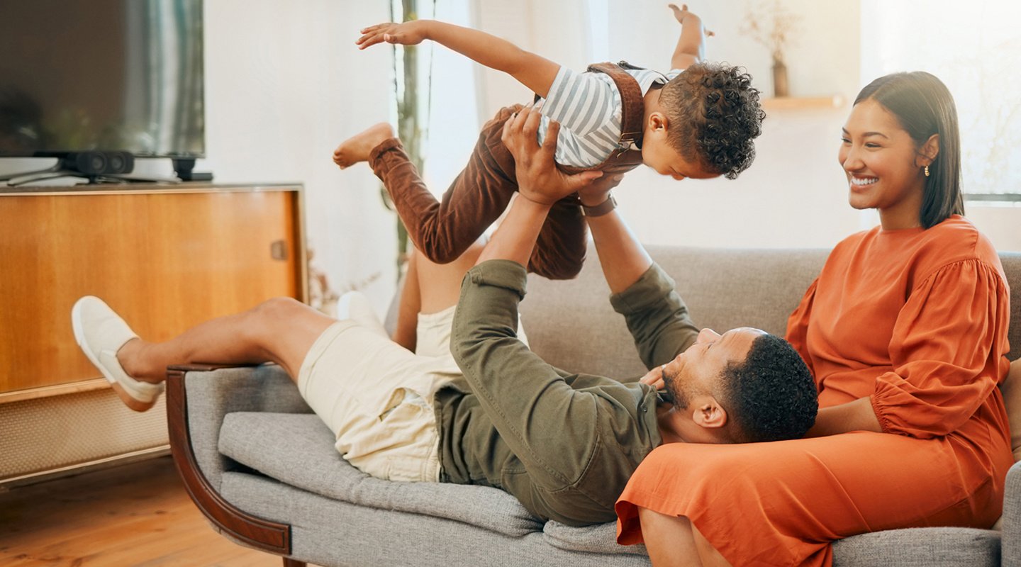 Mom, dad and son on couch playing airplane