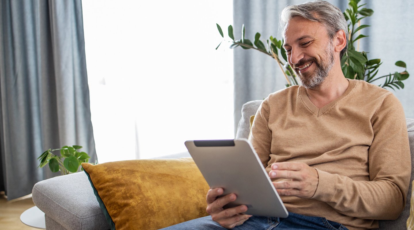 Man on tablet on couch at home