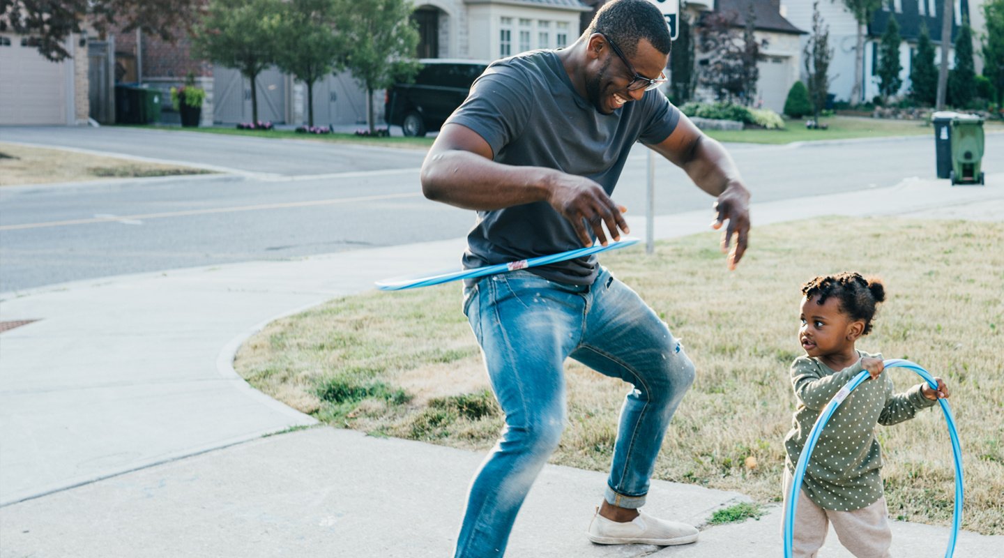 Dad and daughter playing hula hoop in yard