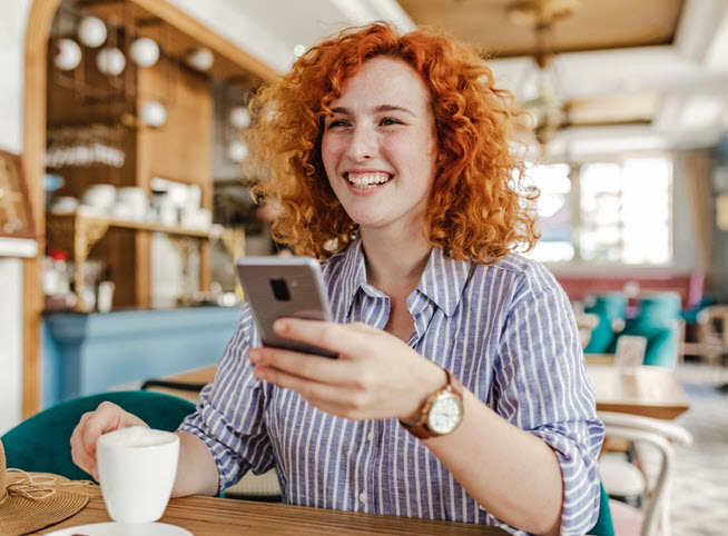 Smiling Woman On Phone In CoffeeShop